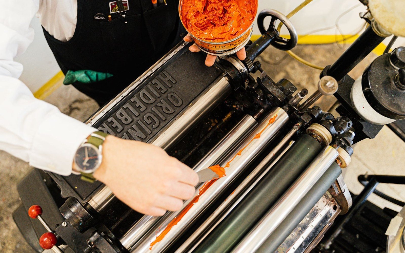 A rubber brayer rolling across a freshly inked flat plate, ink spreading evenly behind it