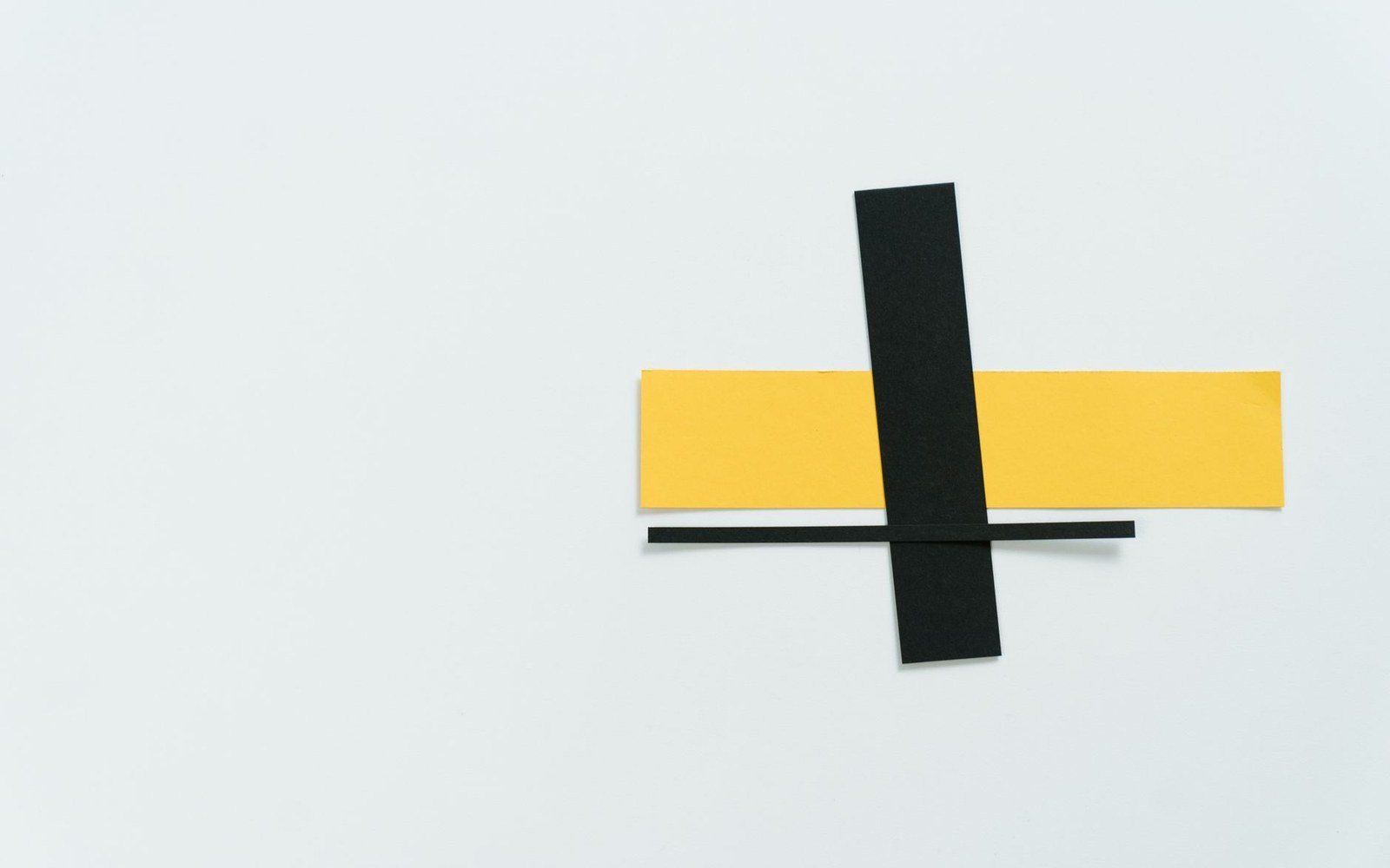 Cut paper strips in black and yellow arranged in an abstract cross composition