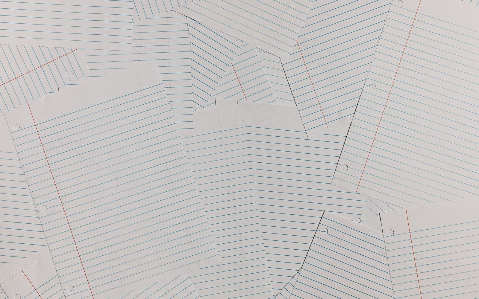 Torn sheets of blue-lined notebook paper overlapping at various angles