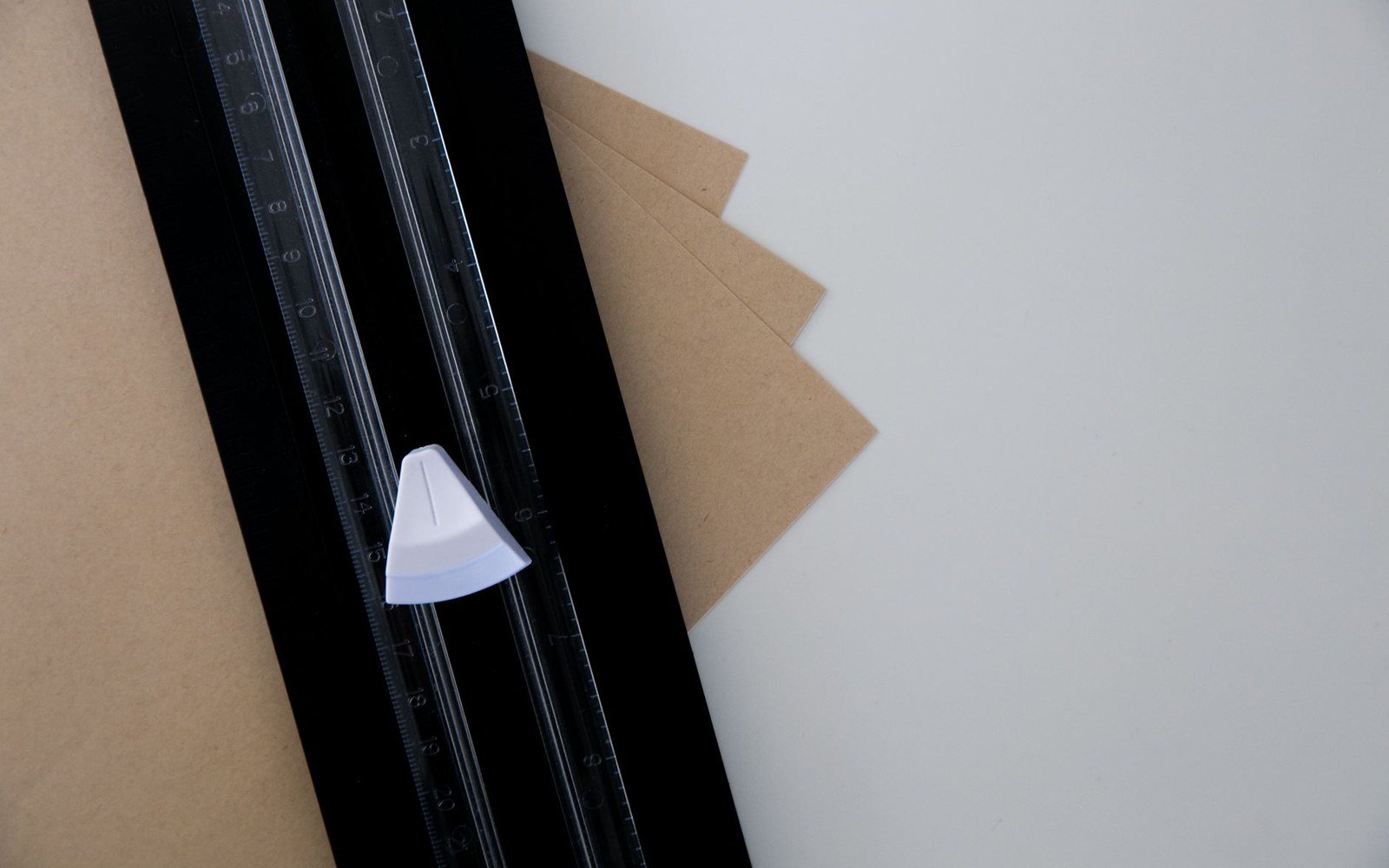 A paper trimmer cutting sheets of brown kraft paper on a white surface