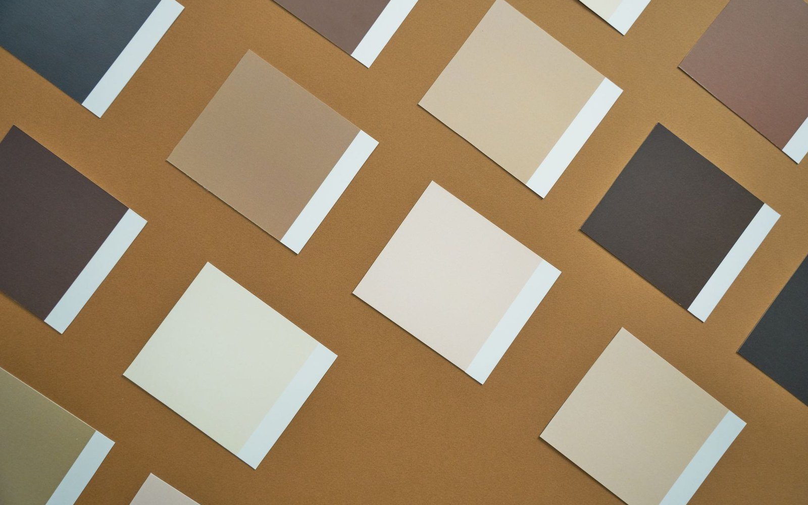 Grid of neutral-toned paper squares arranged diagonally on a brown background