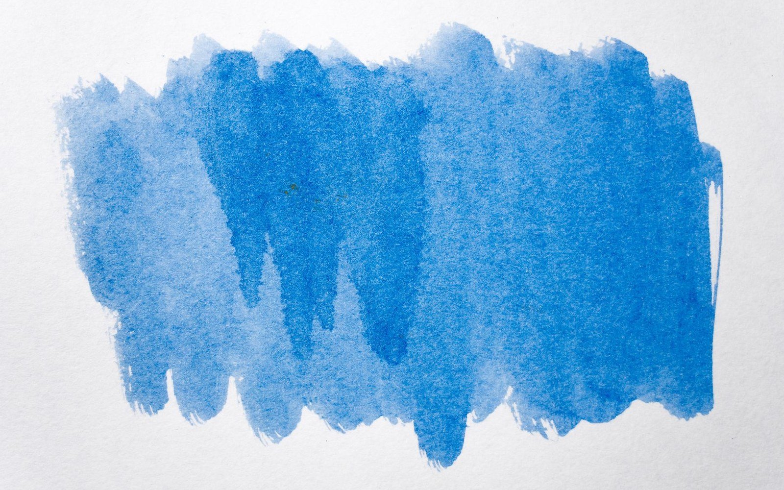 Blue watercolor paint brushed unevenly across white textured paper