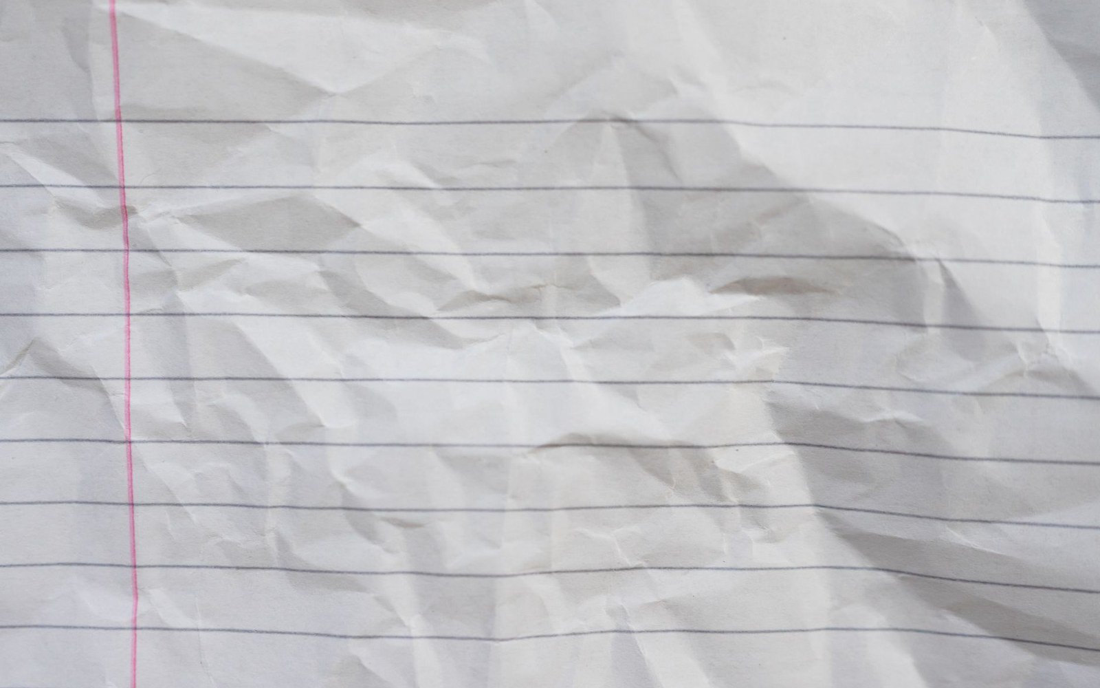 Crumpled sheet of lined notebook paper with a red margin line